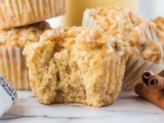 some muffins are sitting on a marble surface with cinnamon sticks next to them