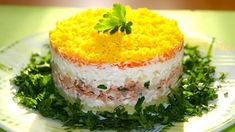 a small cake on a white plate with green and yellow toppings, garnished with parsley