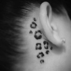 a woman's ear with leopard print on the back of her left ear and behind it is a black and white photo