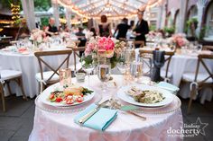 the table is set with plates and silverware for an elegant wedding reception in a tented area