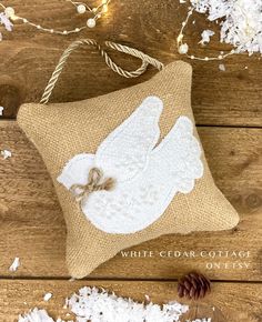 a white angel pillow sitting on top of a wooden floor next to a pine cone