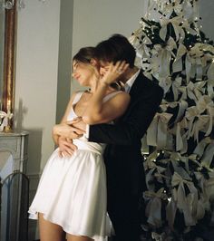 a man and woman embracing in front of a christmas tree