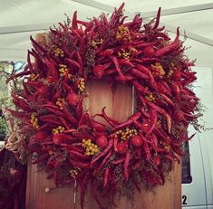 a wreath made out of red peppers on top of a wooden board next to a white van