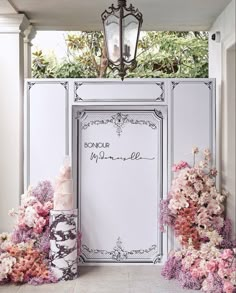 there are many flowers on the floor and in front of an ornate frame with a sign