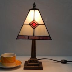 a lamp that is on top of a table next to a cup and saucer