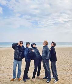 four people are standing on the beach posing for a photo