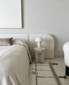 a bedroom with a white bed and rugs on the floor next to a lamp