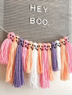 some tassels are hanging on a wall with the words hey boo written above them