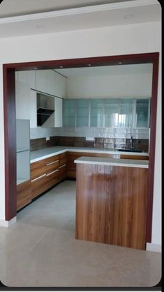 an empty kitchen with wooden cabinets and marble counter tops, is seen from the doorway