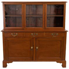 a wooden china cabinet with glass doors on the top and bottom shelves, in front of a white background