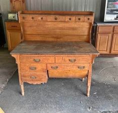 an old wooden desk with two drawers and a drawer on the bottom, sitting in a garage