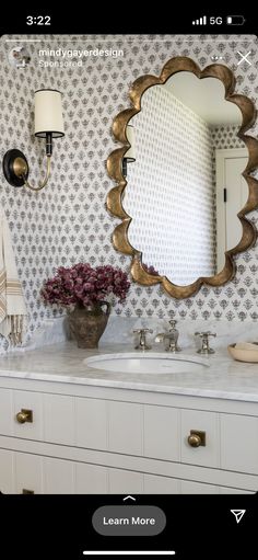 a bathroom vanity with two sinks and a large gold mirror above it, on the wall