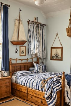 a bed room with a neatly made bed and two hanging sailboats on the wall