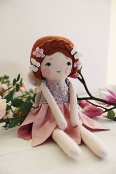 a stuffed doll sitting on top of a table next to flowers