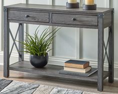 a table with two drawers and a potted plant on top of it next to a rug