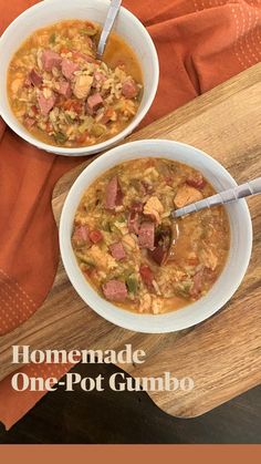 two bowls of soup are sitting on a cutting board with an orange napkin and spoon