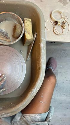 a person with their hands in a bowl and some other items on the table next to them