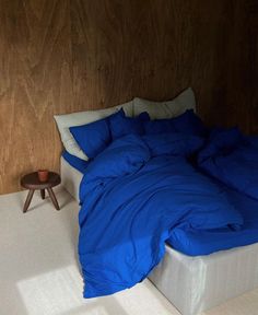 a bed with blue sheets and pillows on top of it next to a night stand