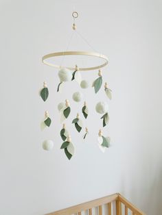 a baby crib with a white and green mobile hanging from it's side