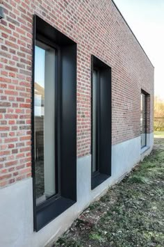 the side of a brick building with three windows and one door open to let in light