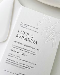 an elegant wedding program is displayed on a white plate with silverware next to it