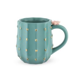 a green ceramic mug with gold studdings on the side and a pink flower sticking out of it