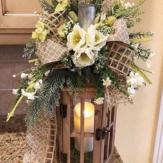 a wooden lantern with flowers and greenery on it