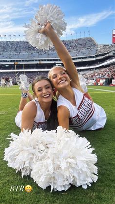 two cheerleaders pose for the camera at a football game