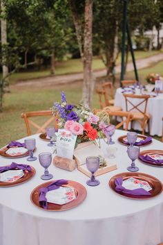 the table is set with purple and white plates, napkins, and flowers on it