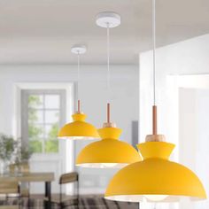 three yellow lamps hanging from the ceiling in a room with chairs and tables around it