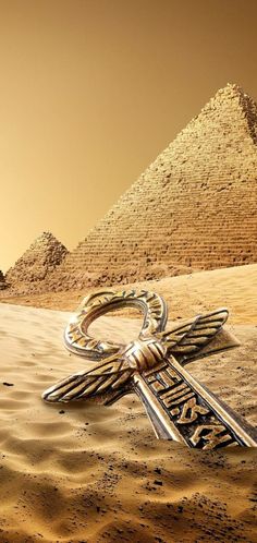 a cross in the desert with pyramids in the background