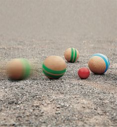 four wooden balls sitting in the sand with one red, one green and one blue