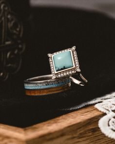 Two handcrafted turquoise wedding rings from Staghead Designs sit on a boho felt hat. One is the "Zara" engagement ring in 14K white gold with a 9x9mm square cabochon turquoise center stone & diamond halo. Below sits the "Dyad" damascus steel wedding band with whiskey barrel oak, turquoise, & elk antler inlays. Western Wedding Rings Sets, Damascus Steel Wedding Band, Western Wedding Rings, Turquoise Wedding Rings, Turquoise Wedding Band, Turquoise Ring Engagement, Unique Wedding Jewelry, Dream Rings, Elk Antler