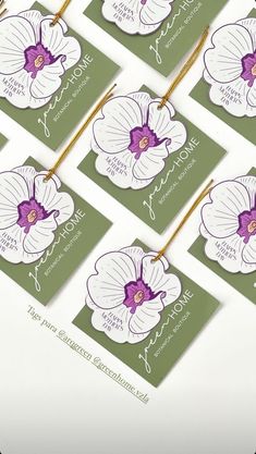 six business cards with purple and white orchids on them, hanging from clothes pins