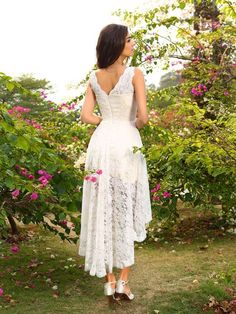 a woman standing in front of flowers wearing a white dress