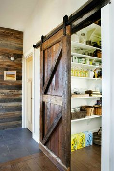 an open barn door in the middle of a room with shelves and baskets on either side