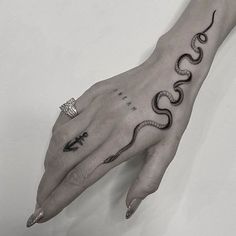 a woman's hand with a snake tattoo on it and an arrow in the middle