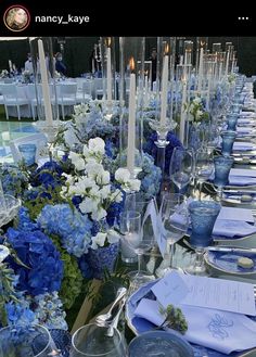 a long table is set with blue and white flowers, silverware, and candles