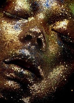 a close up of a person with glitter all over their face and body, looking to the side