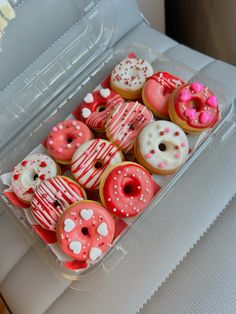 a plastic container filled with pink and white donuts