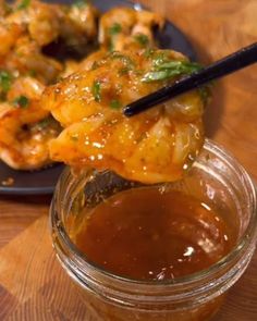 some food is on a plate with chopsticks and sauce in a glass jar