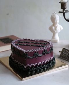 a heart shaped cake sitting on top of a table next to a candle and book