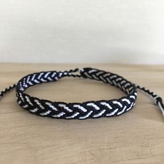 a black and white braided bracelet sitting on top of a wooden table