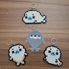 four pixellated keychains are shown on a wooden surface, one is white and the other is black