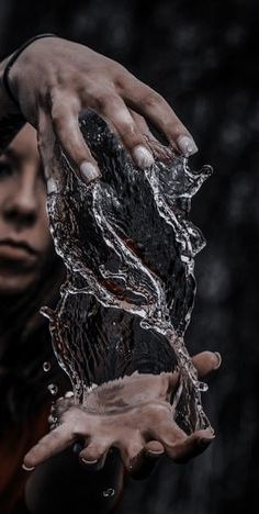 a woman holding her hands in the air with water splashing on her face and arm