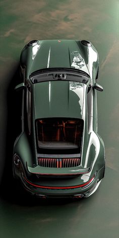 an overhead view of a green sports car with its hood up and the lights on