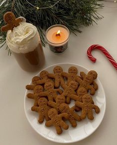 gingerbreads are arranged on a plate next to a cup of coffee and candy cane