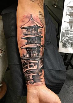 a person with a tattoo on their arm that has a building in the middle of it