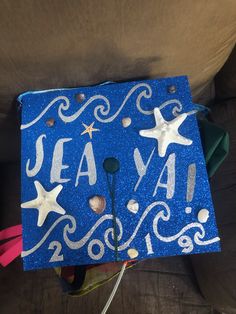 a blue graduation cap with white stars and the words sea ya on it is sitting on a couch