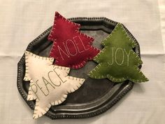 three felt christmas trees sitting on top of a metal tray with the word noel spelled out